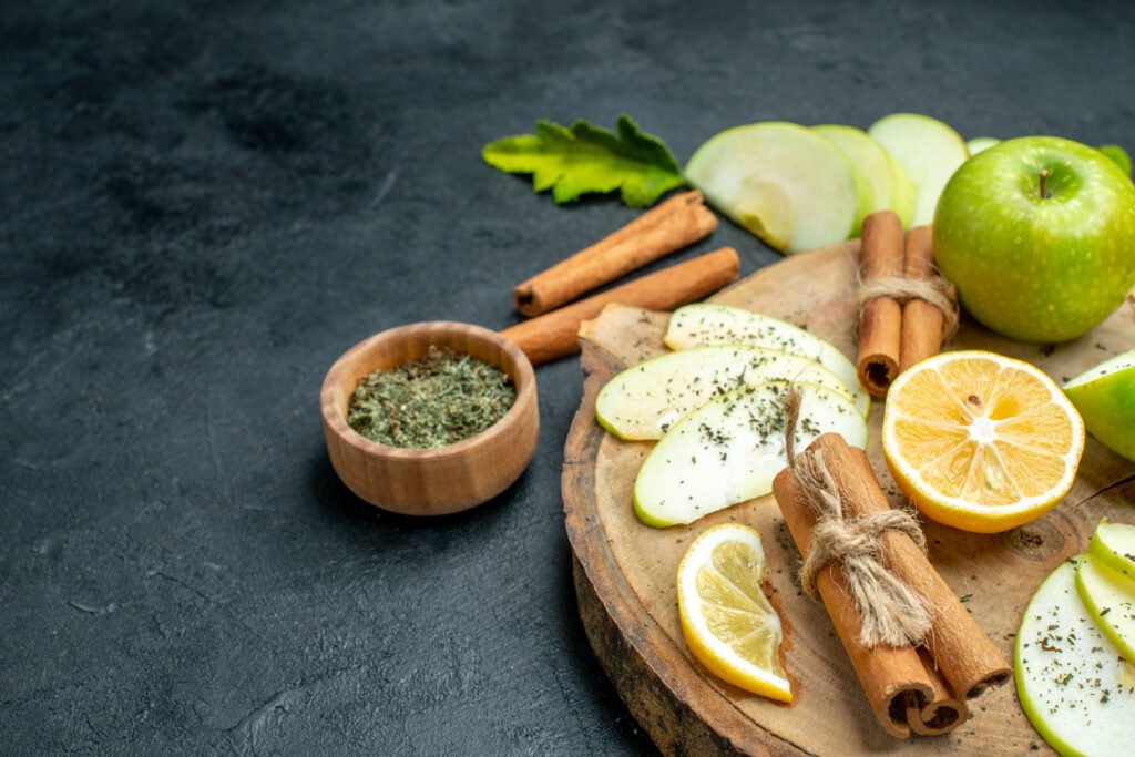 10 Best Home Remedies for Teeth Pain, Sensitivity & Bleeding bottom view apple slices apple tied cinnamon sticks lemon slices wood board with dried mint powder black ground copy place